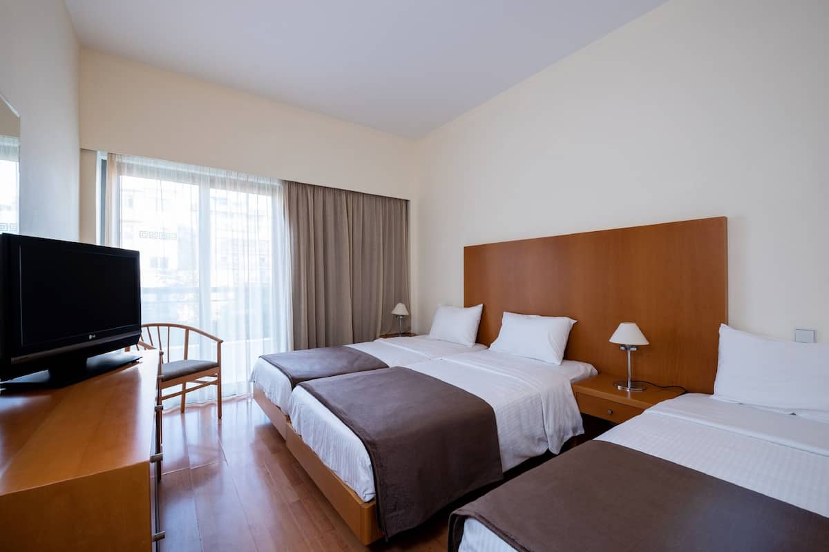 Habitación de hotel con dos camas, un televisor, un escritorio y una silla.
