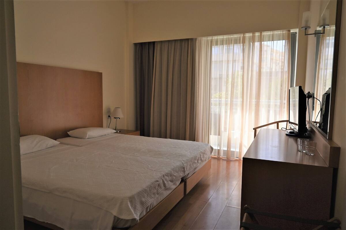 Una habitación de hotel con una cama grande, un escritorio y una televisión.