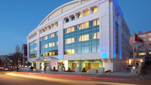 Un hotel moderno con fachada curva, ventanas amplias y una entrada bien iluminada.