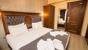 A neatly made bed with white linens and towels, a wooden headboard, and a large mirror above the bed. - Ala Sofia Hotel (Istanbul)