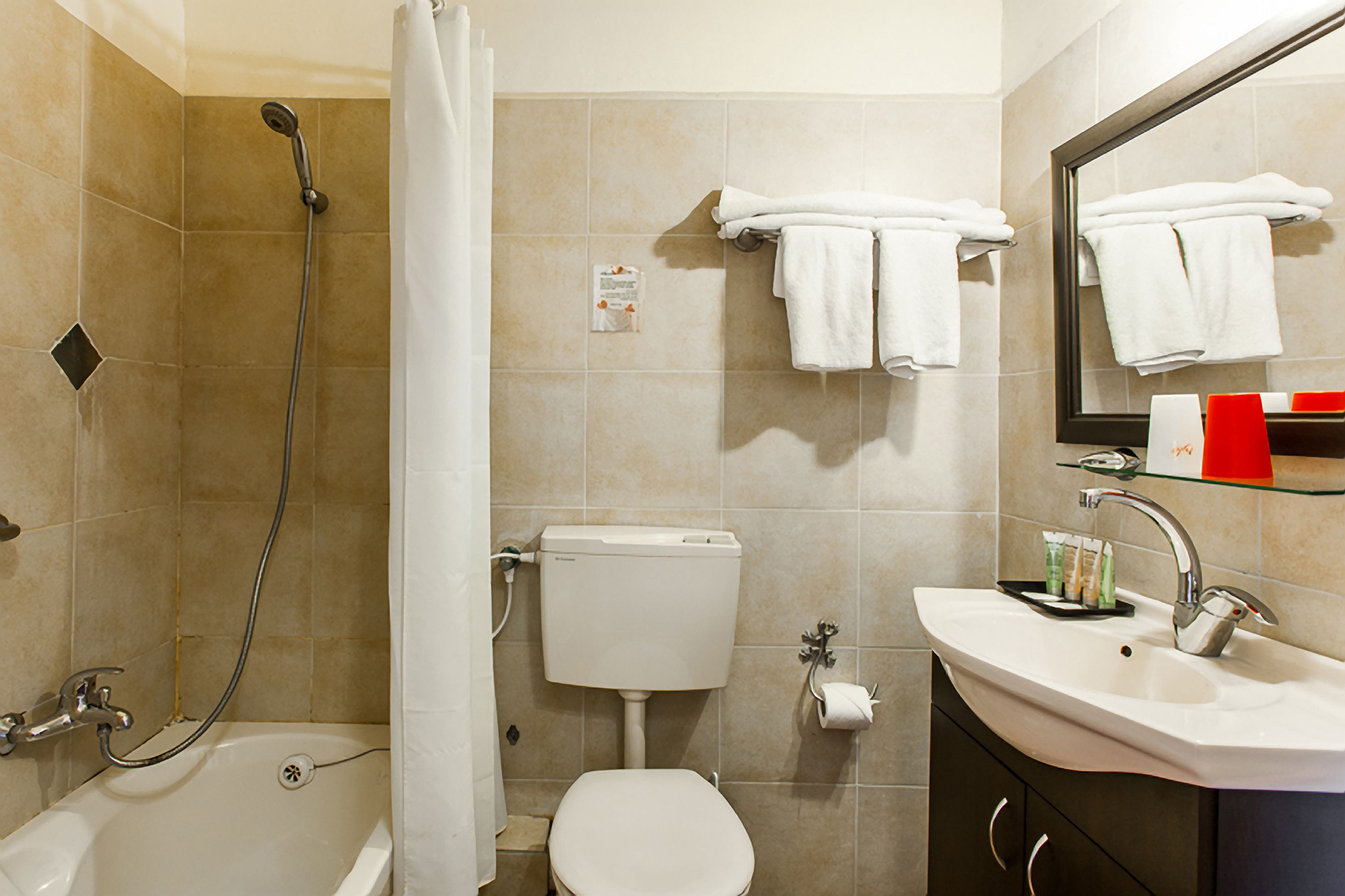 Et badeværelse med badekar, toilet, vask og en bruser med glasvæg.