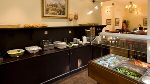 A buffet area with various food items, a framed picture on the wall, and a chandelier in the dining area. - Little House in Rehavia (Jerusalem)