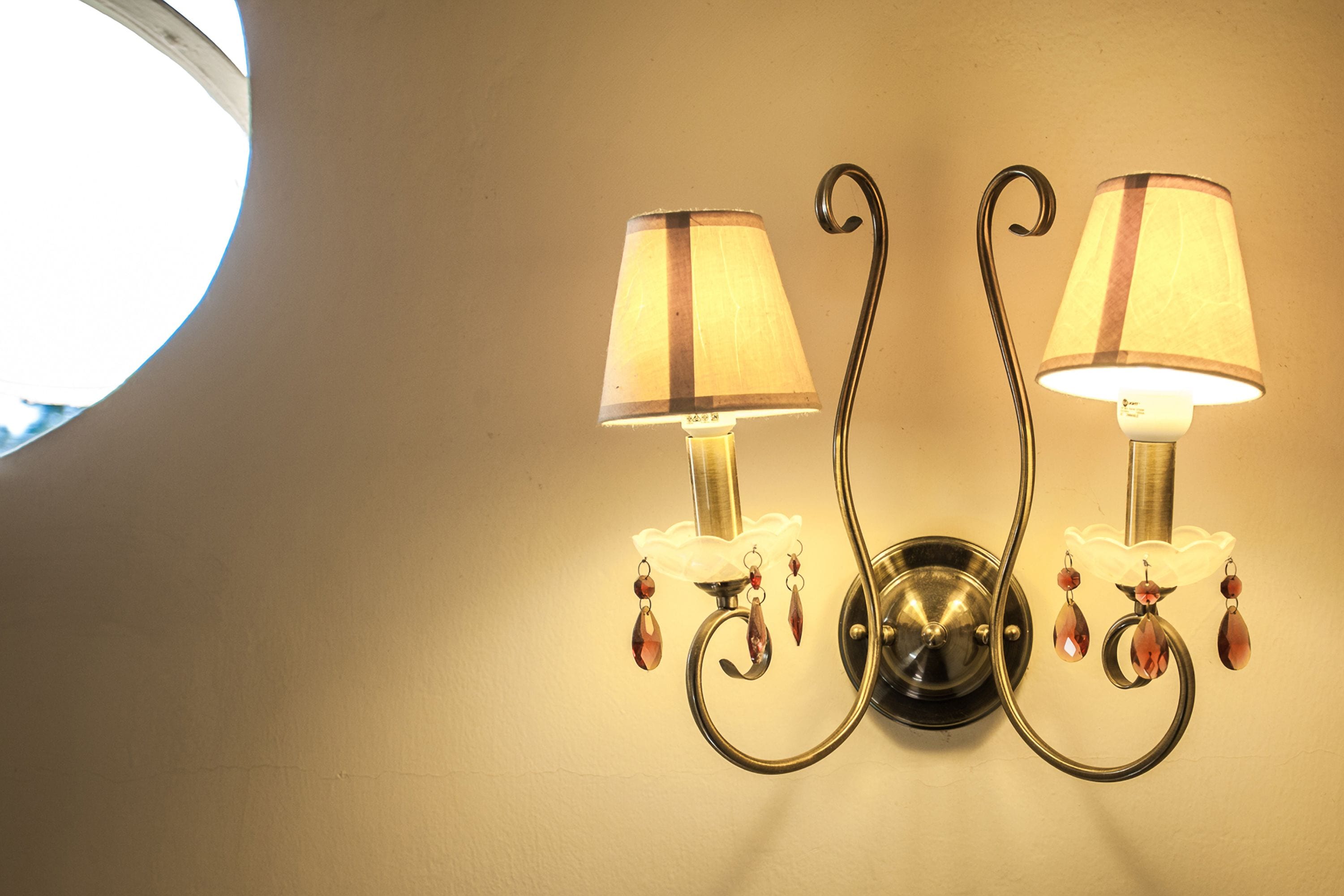 A wall-mounted light fixture with two lamps and decorative elements.