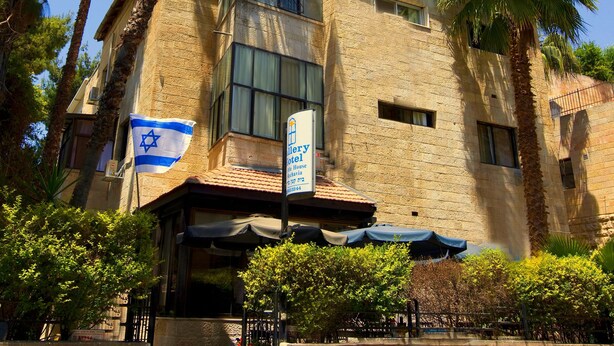 A building with a stone facade, a flag, and a sign for the "Gallery Hotel." - Little House in Rehavia (Jerusalem)