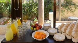 A breakfast buffet with fruit bowls, plates, and glasses. - Little House in Rehavia (Jerusalem)