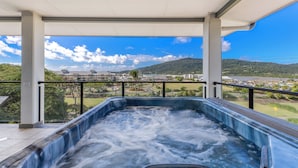 Un jacuzzi sur un balcon offrant une vue sur la ville et les collines environnantes.