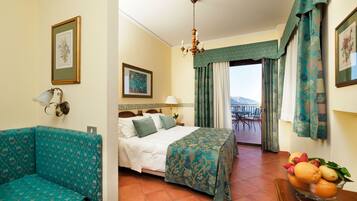 Ein Hotelzimmer mit Bett, Sofa, Balkon mit Tisch und Stühlen sowie Obstschale.