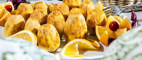 Een bord met goudbruine gebakjes, oranjeslices en een kers.