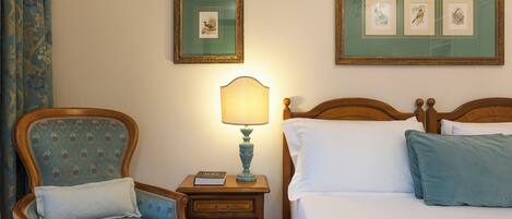 Une chambre à coucher avec un lit, une table de chevet avec une lampe, une chaise et deux tableaux encadrés au mur.