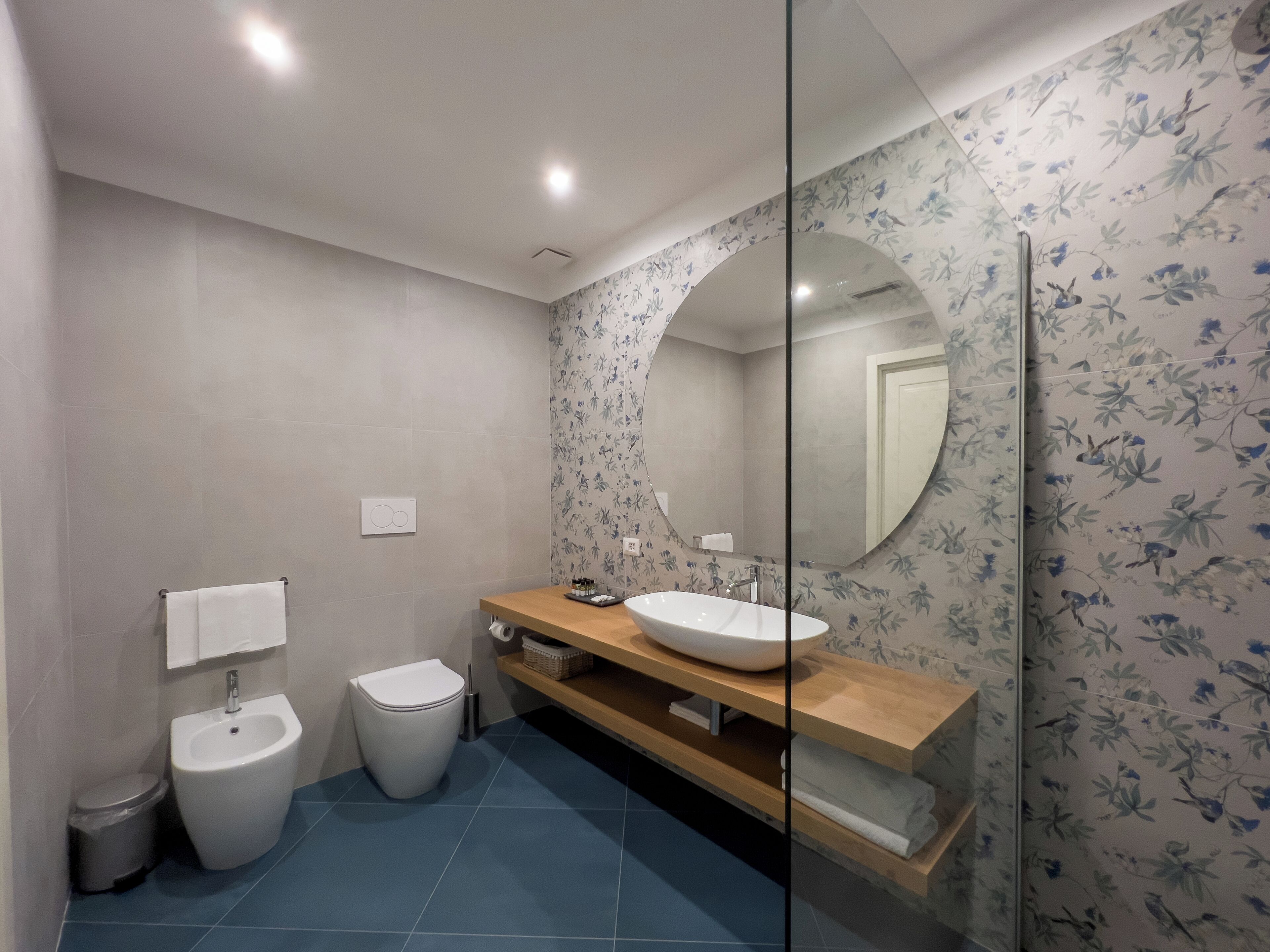 Une salle de bain moderne avec une douche à l’italienne en verre, un lavabo blanc et un bidet.