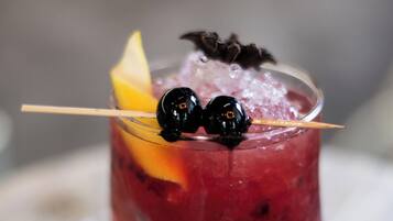 A cocktail with a lime wedge and a decorative fruit on a glass with a straw.