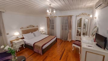 A well-appointed hotel room with a large bed, a vanity with a mirror, a television, and a desk with a lamp.