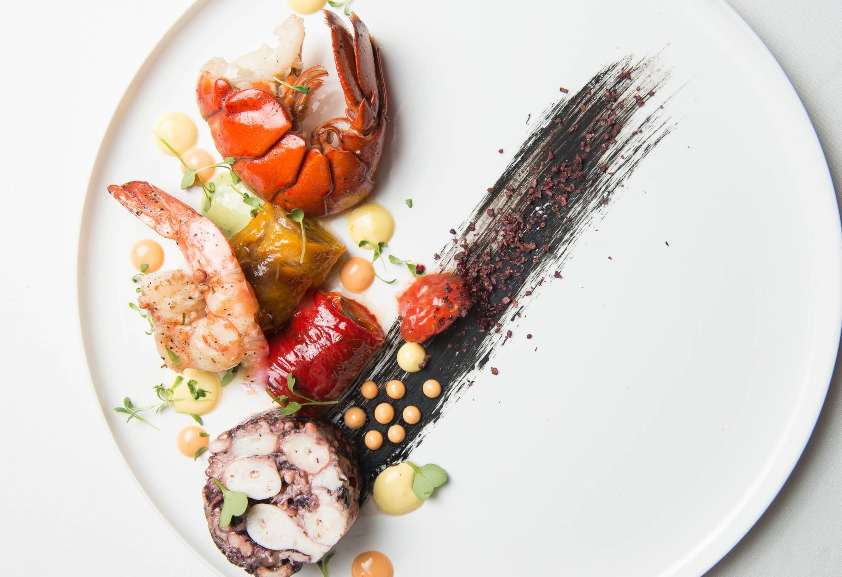 A white plate with a variety of seafood including shrimp, crab, and a roll of seafood.
