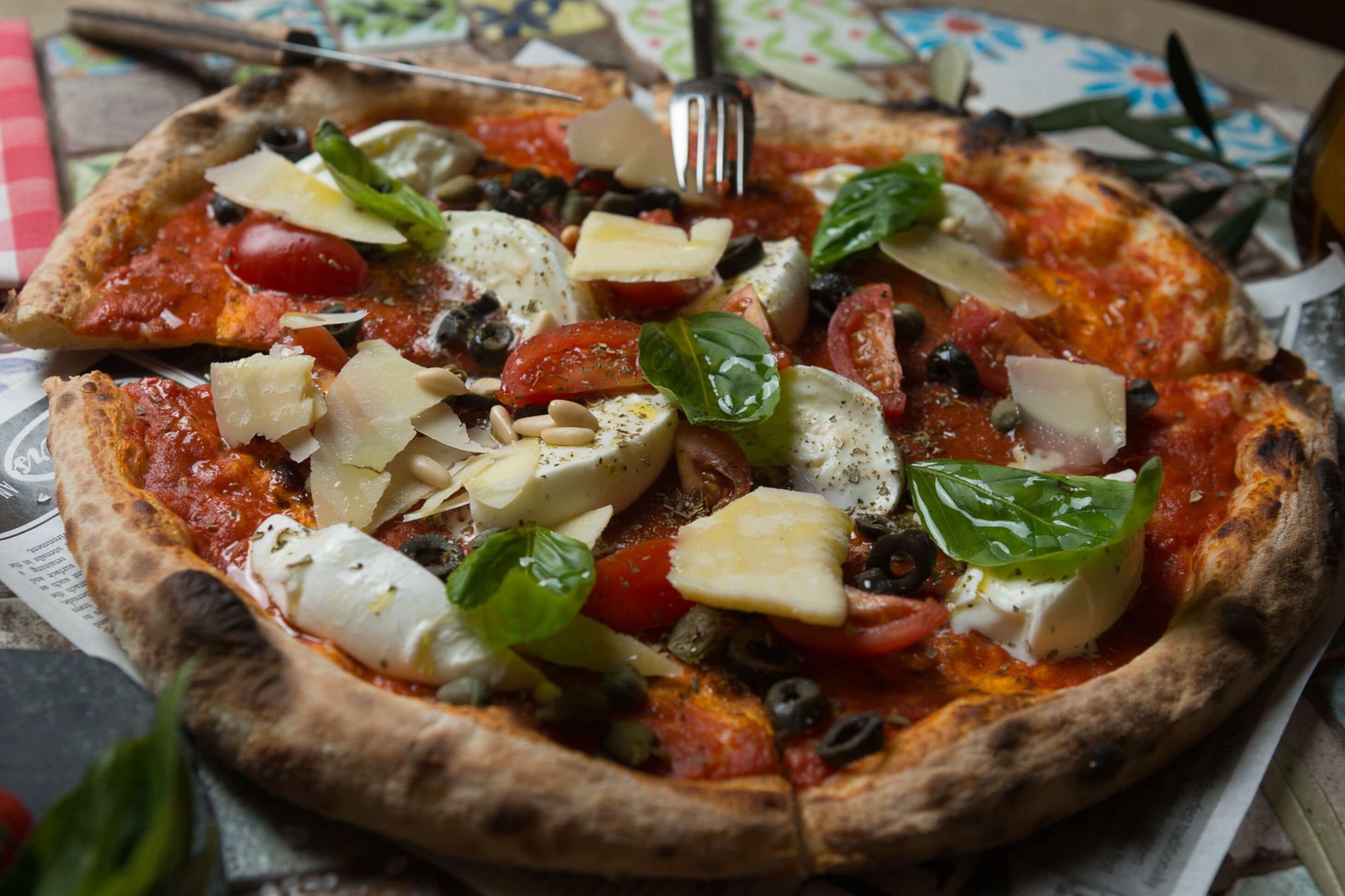 Una pizza con varios ingredientes, incluyendo tomates, queso y albahaca.