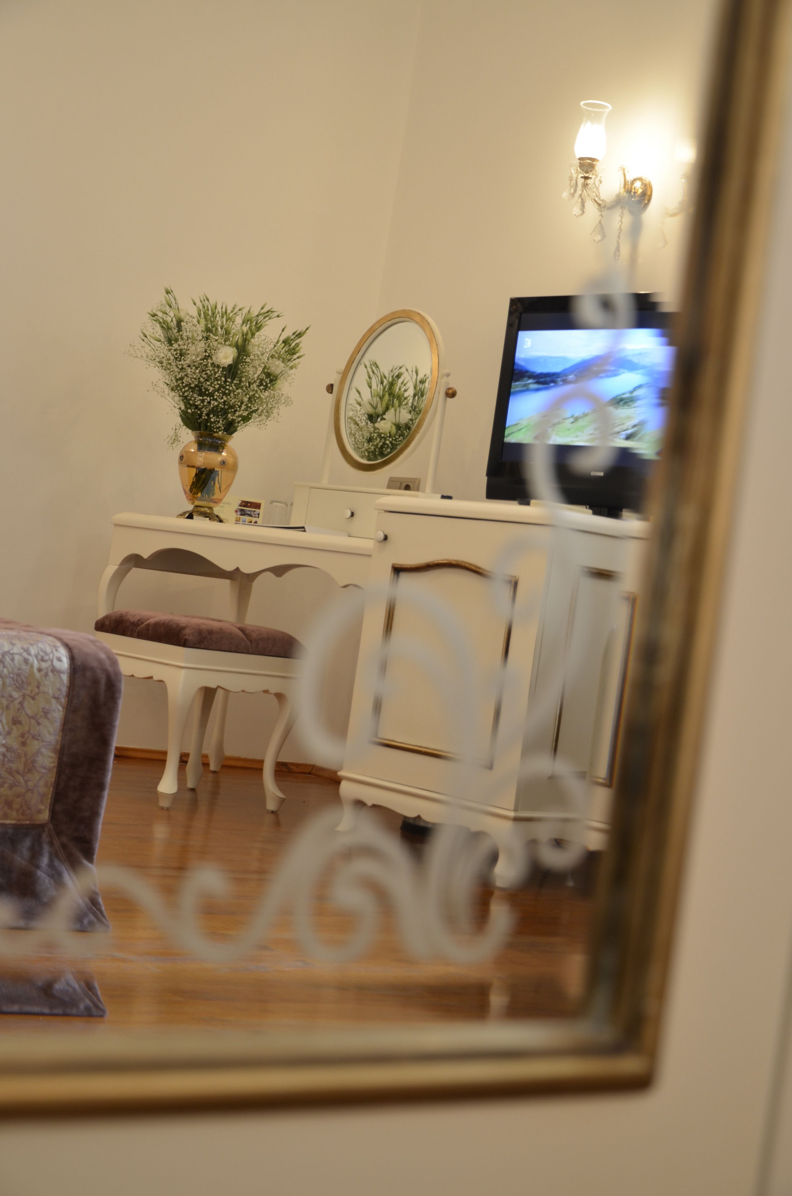 Un dormitorio con tocador, espejo, televisor y una planta decorativa.