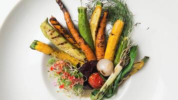 Un plato blanco con verduras a la parrilla y hojas verdes.