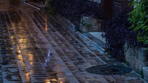 A narrow, wet cobblestone alley with stone walls, a wooden door, and hanging lanterns. - Tuvana Hotel - Special Class (Antalya)