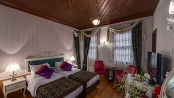 A hotel room with two beds, a TV, a small table, and a red chair.