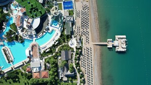 Ein Luftbild eines Resorts mit mehreren Schwimmbecken, einem Strand und einer Anlegestelle.