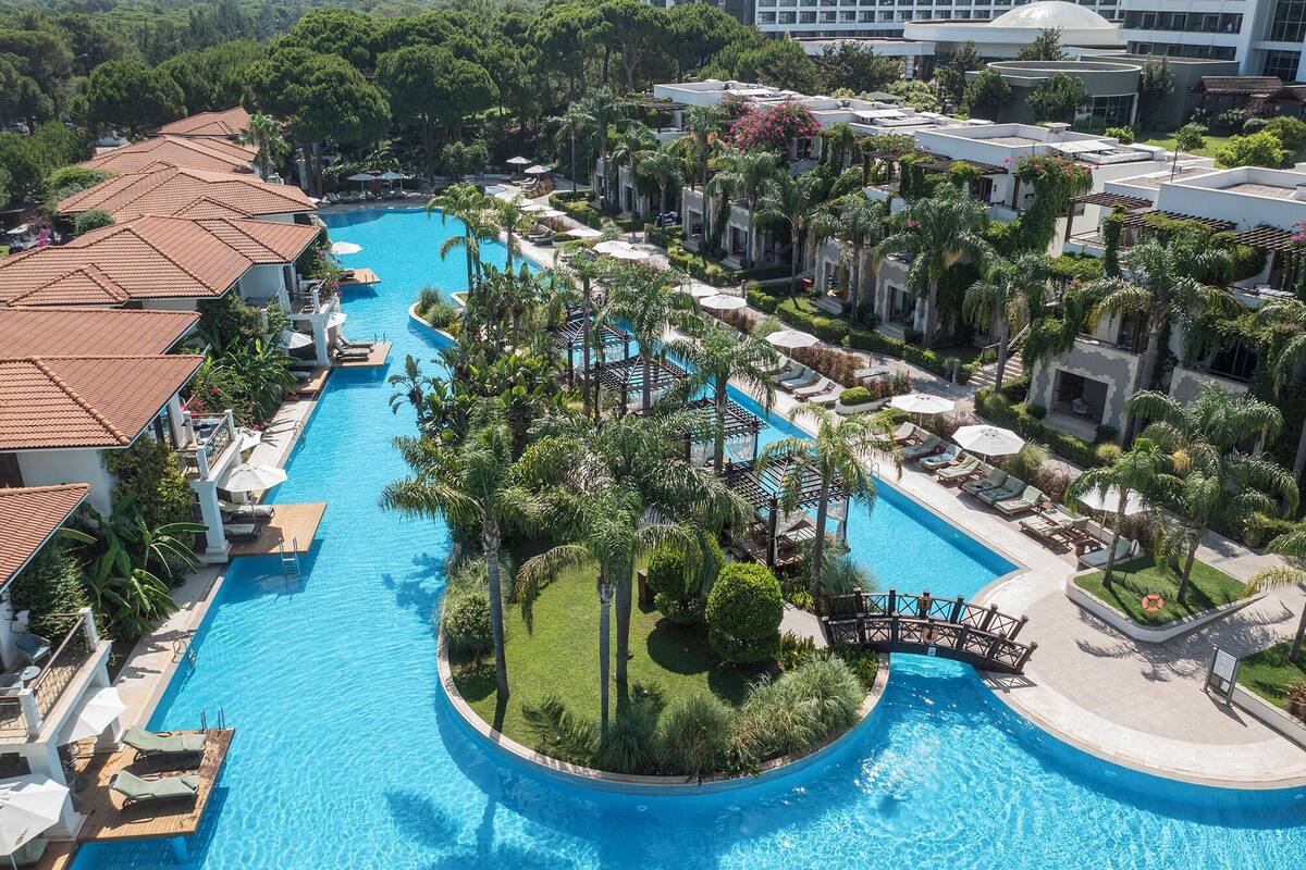 Ein Resort mit einem zentral gelegenen Schwimmbad, umgeben von Palmen und Liegebereichen.