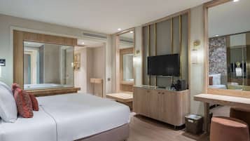 Quarto de hotel moderno com uma cama grande, uma televisão, uma toucador de madeira e um espelho grande.