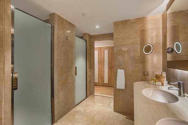 A modern bathroom with a glass shower enclosure, a vanity with a sink, and a mirror with two round mirrors.