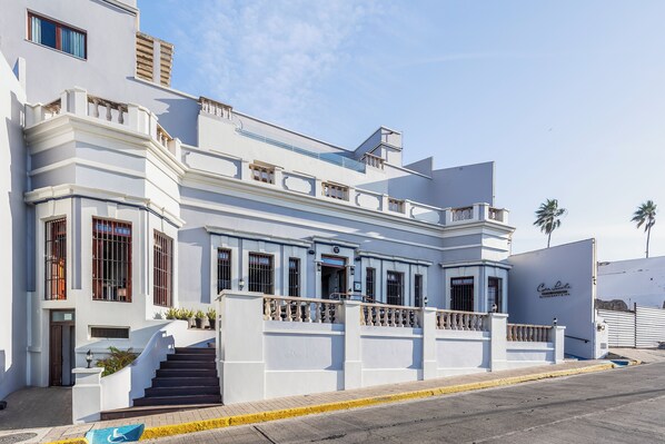 A white building with a staircase leading to the entrance, a balcony, and a sign that reads "Casa de Lujo". - Casa Lucila Mazatlán Curamoria Collection - Adults Only (Mazatlán)