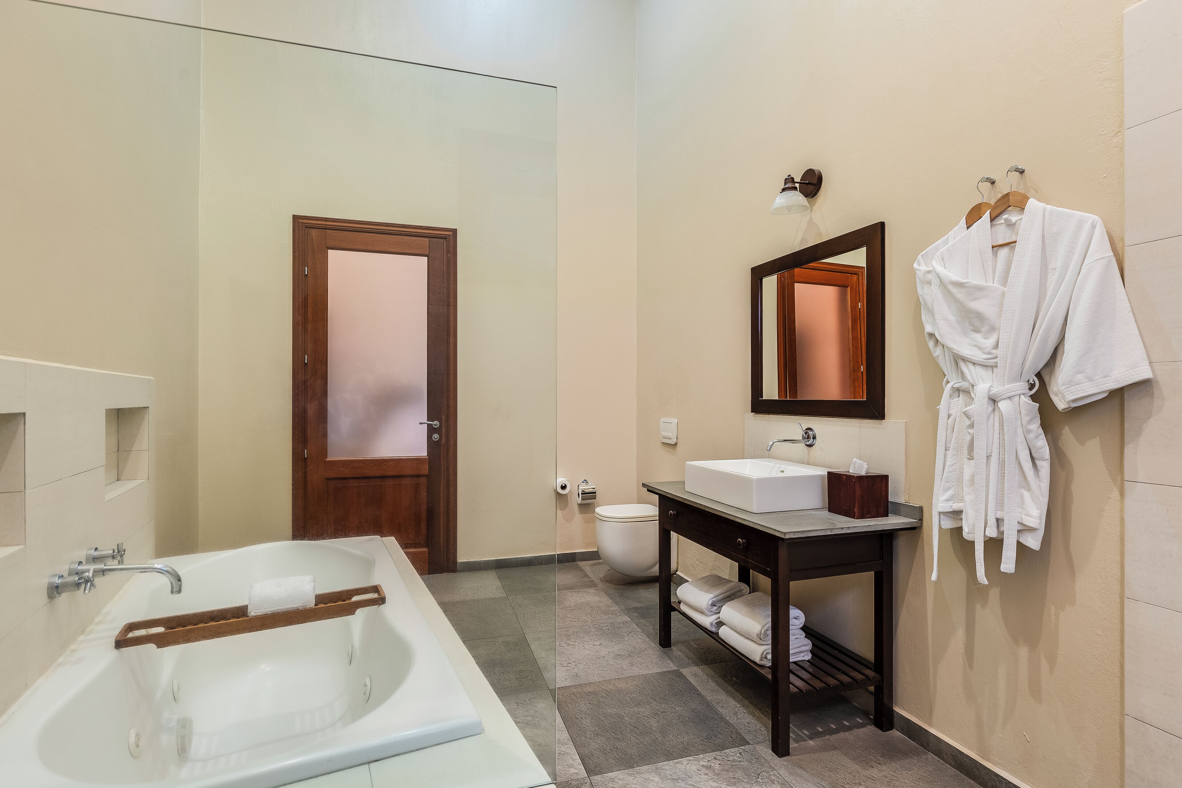 Een moderne badkamer met een bad, een wastafel, een toilet en een spiegel.