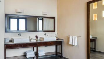 A bathroom with a large mirror, two sinks, and a towel rack.