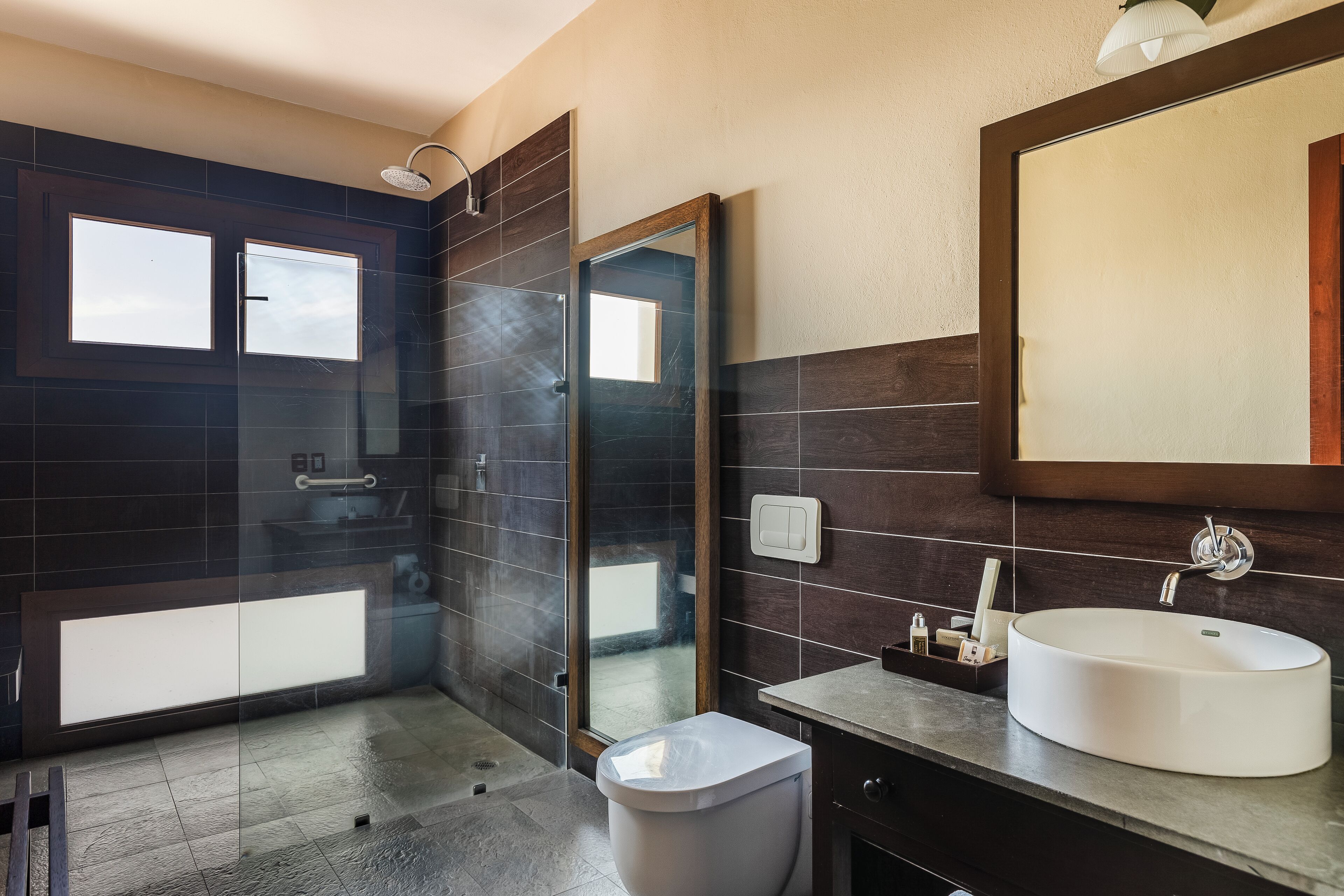 Un baño moderno con cabina de ducha de vidrio, lavabo blanco y un espejo grande.