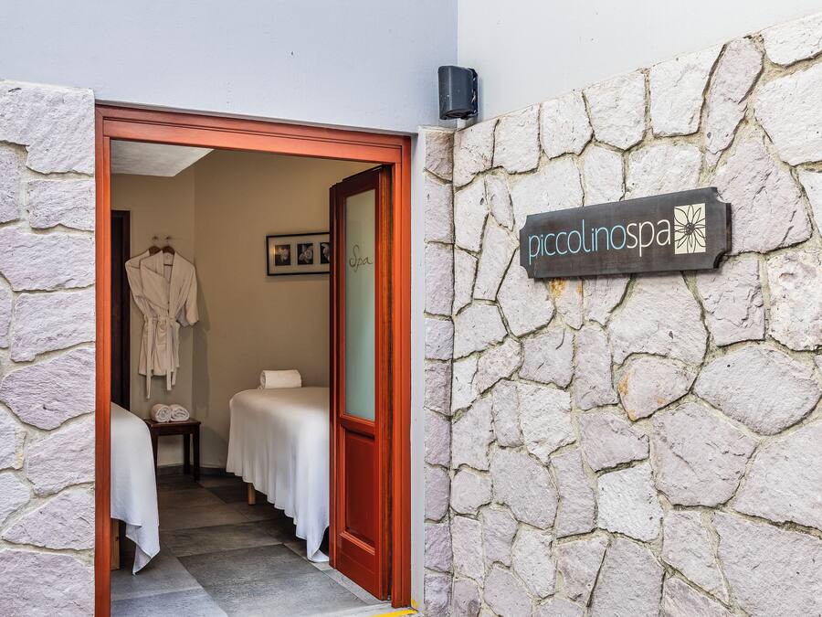 A spa entrance with a stone wall and a sign reading "piccolinospa".