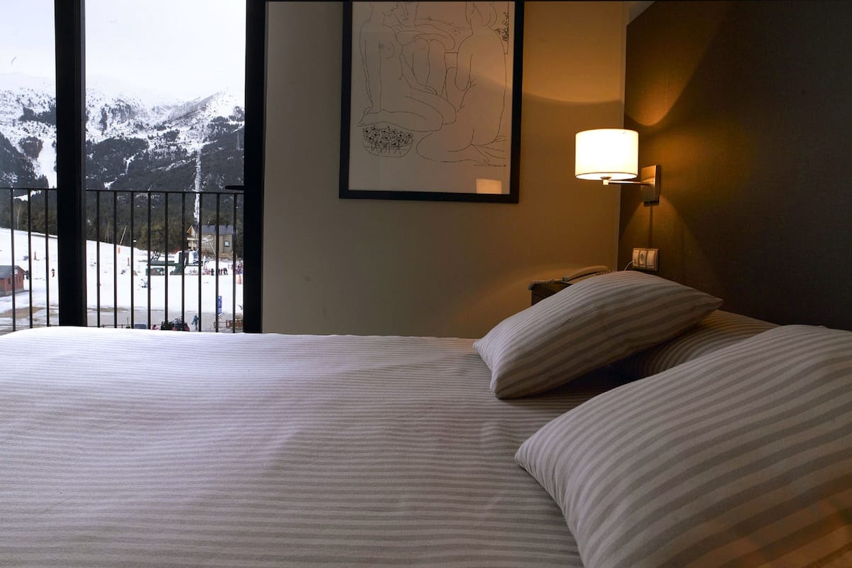 Habitación de hotel con una cama, una mesita de noche, una lámpara y un cuadro en la pared.