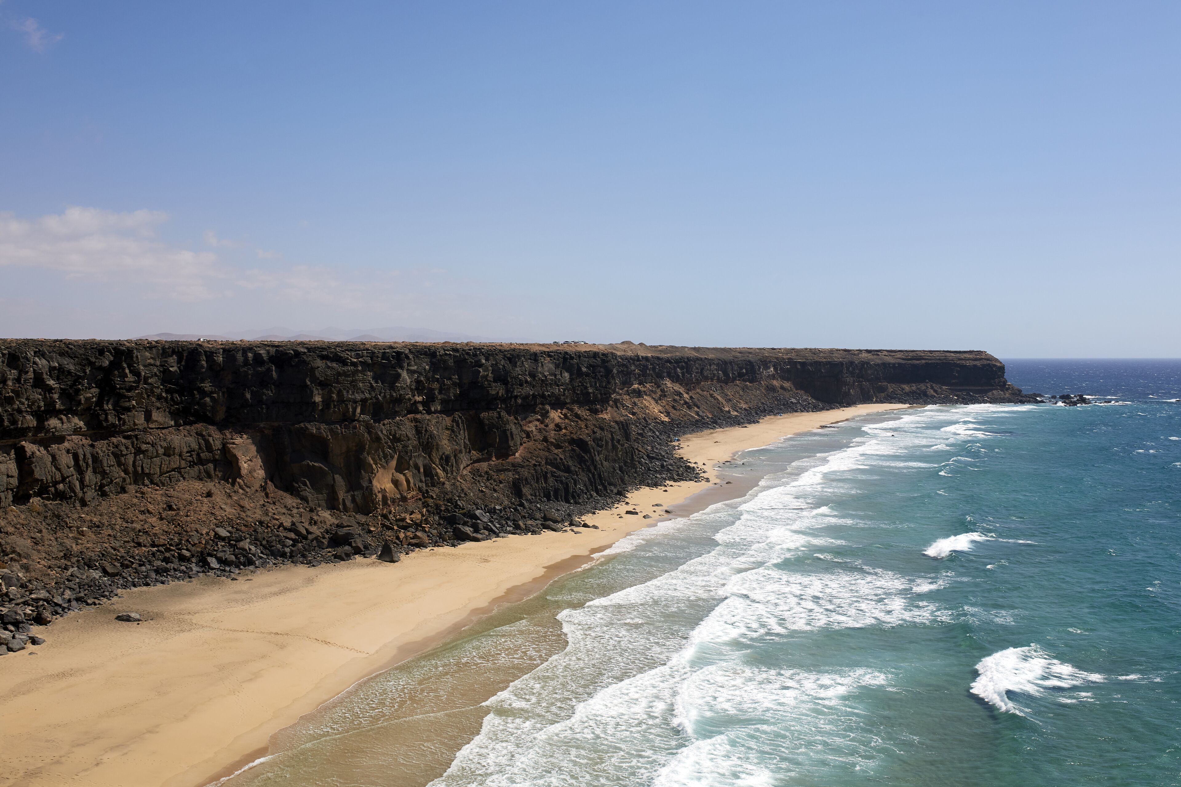 Un paisaje costero con una playa arenosa y acantilados rocosos.