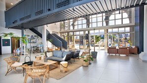 A spacious indoor area with a high ceiling, large windows, and a staircase leading to an upper level. - Coral Cotillo Beach (La Oliva)