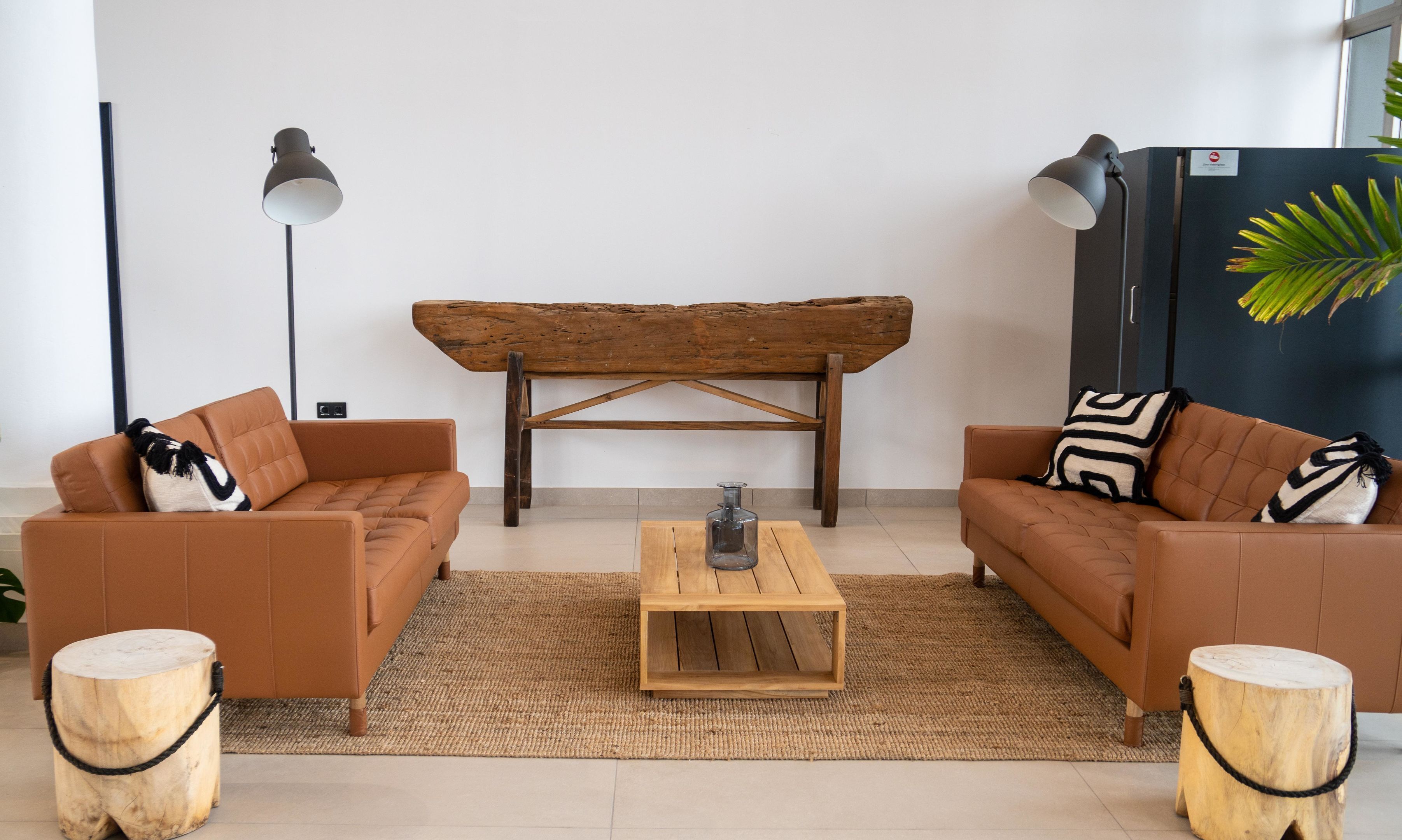A modern living room with two brown sofas, a wooden coffee table, and a unique wooden bench.