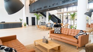 A spacious lobby with a high ceiling, a staircase, and a seating area with a leather sofa and chairs. - Coral Cotillo Beach (La Oliva)