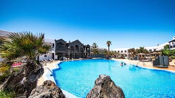 Una piscina al aire libre, sombrillas, tumbonas