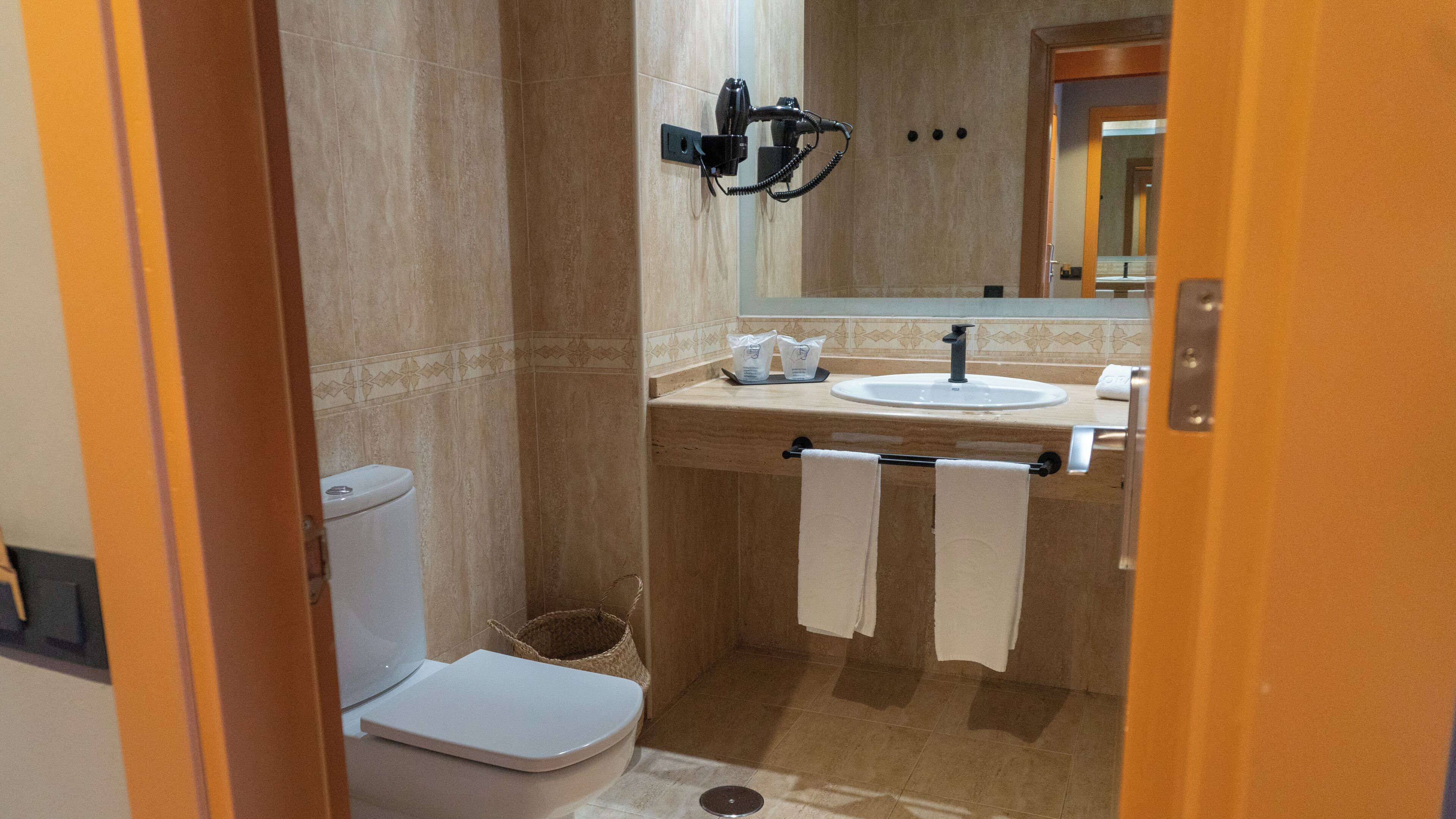 A compact bathroom with a toilet, sink, and towel rack.