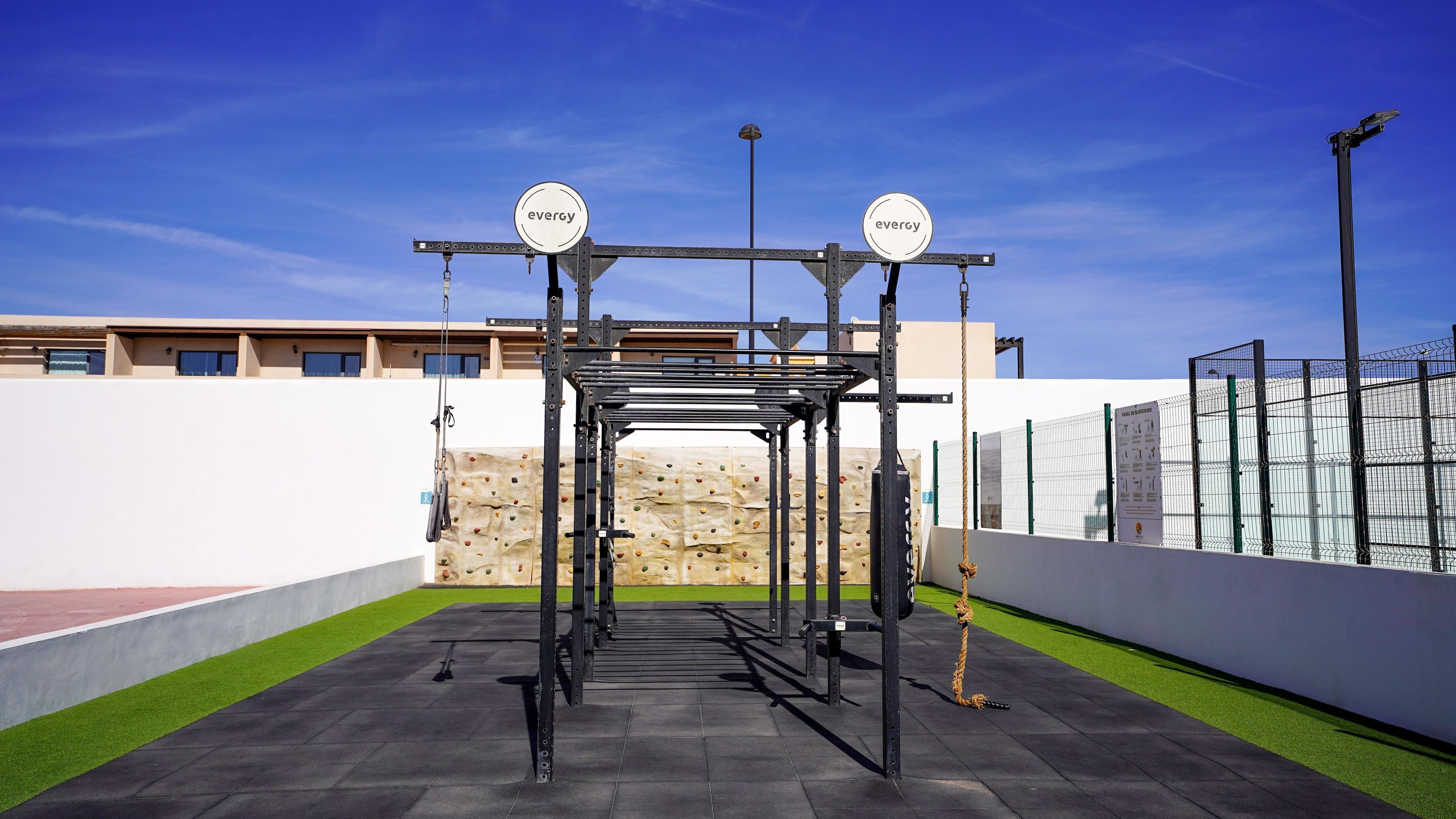 Un gimnasio al aire libre con estructura metálica, cuerdas y pared de escalada.