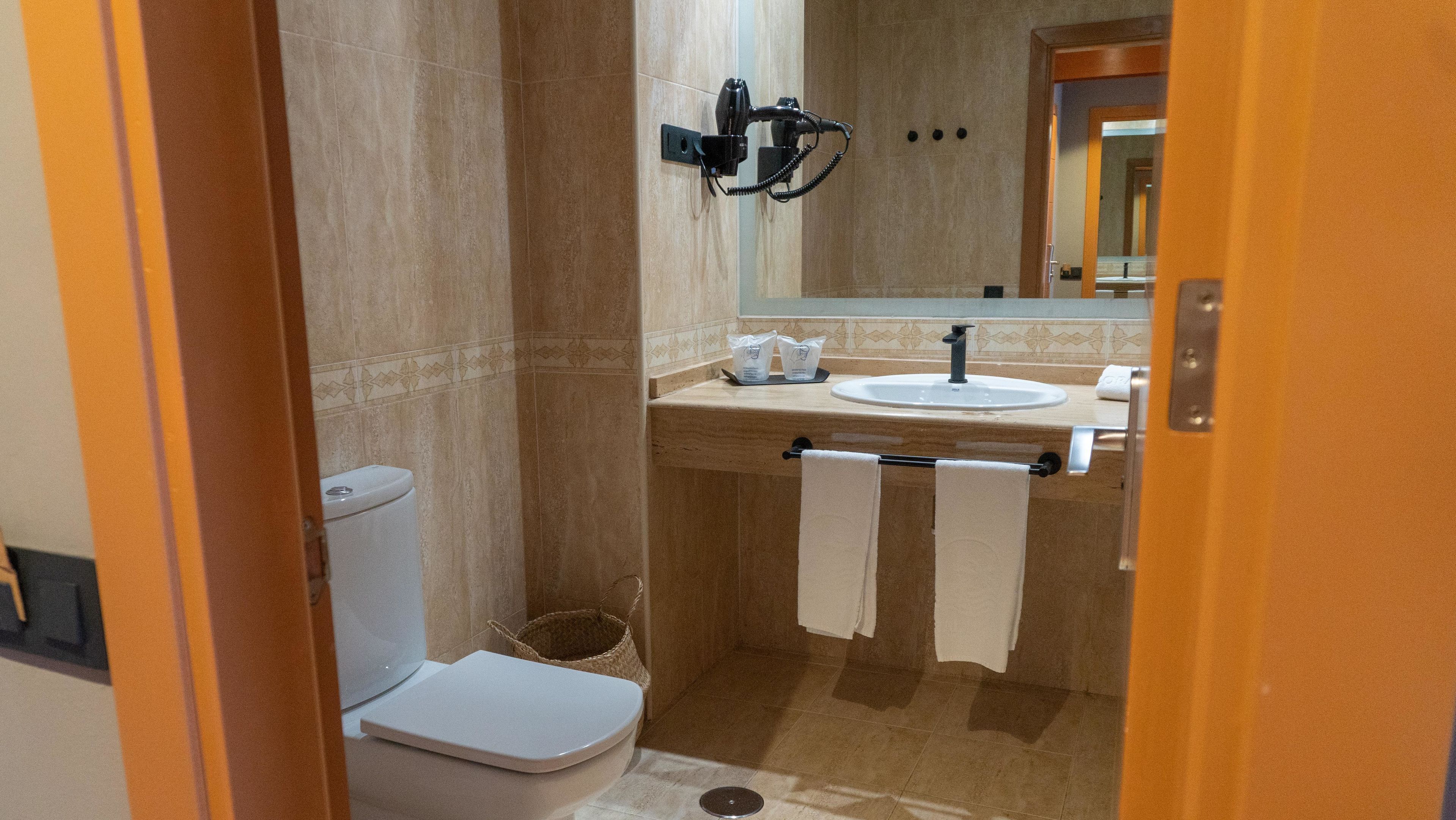A compact bathroom with a toilet, sink, and towel rack.