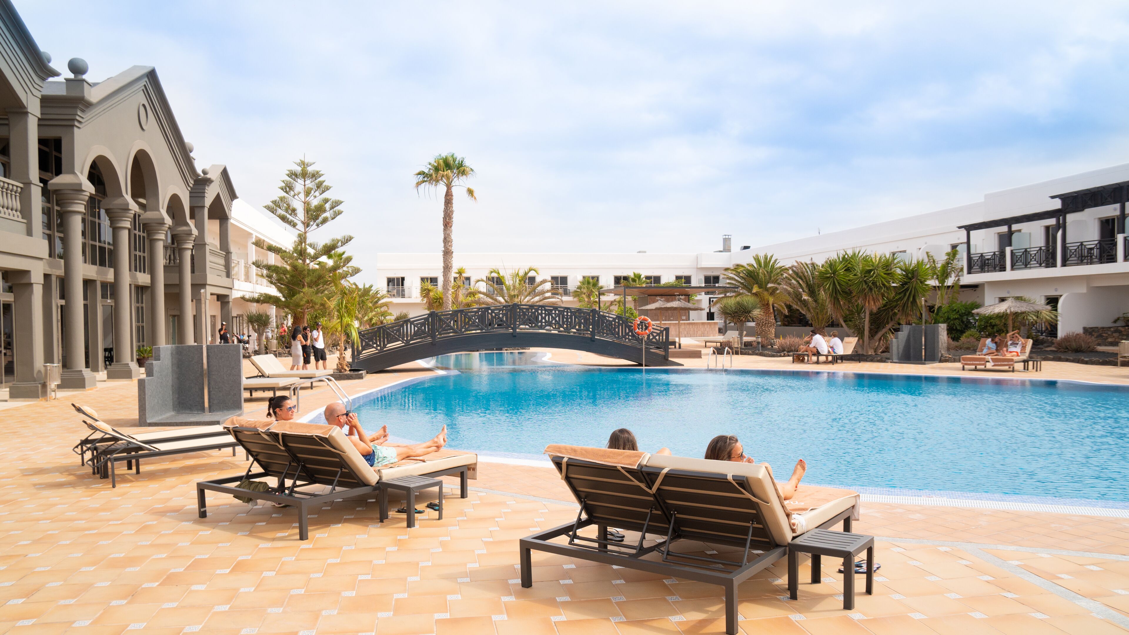 Un espace piscine avec des chaises longues et un pont.