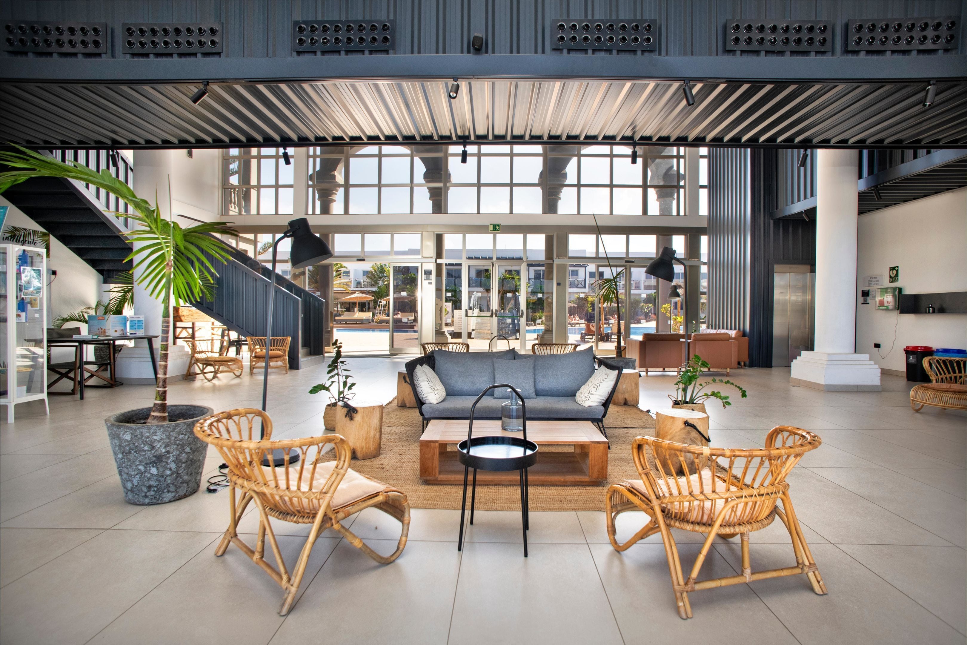 A spacious lobby with a sofa, chairs, a coffee table, and potted plants.
