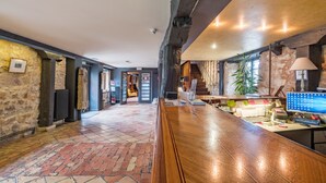 Un espace d’accueil avec un comptoir de réception en bois, un ordinateur et une plante.