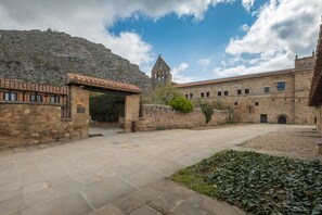 Un patio con edificios de piedra, una torre de campanas y una puerta de piedra.
