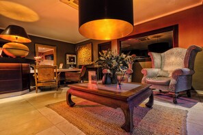 A well-lit living room with a large armchair, a wooden coffee table, and a vase of flowers.