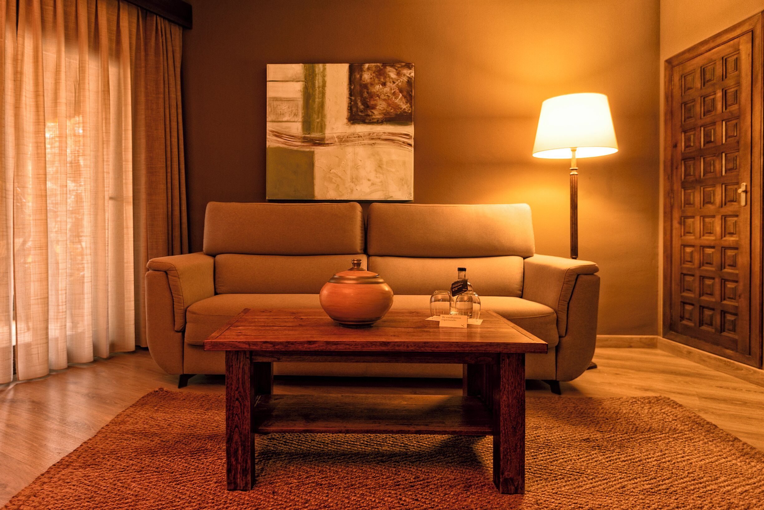 A living room with a sofa, a wooden coffee table, a vase, and a lamp.