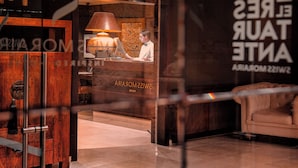 A hotel lobby with a reception desk, a lamp, and a sofa. - Hotel Swiss Moraira (Teulada)