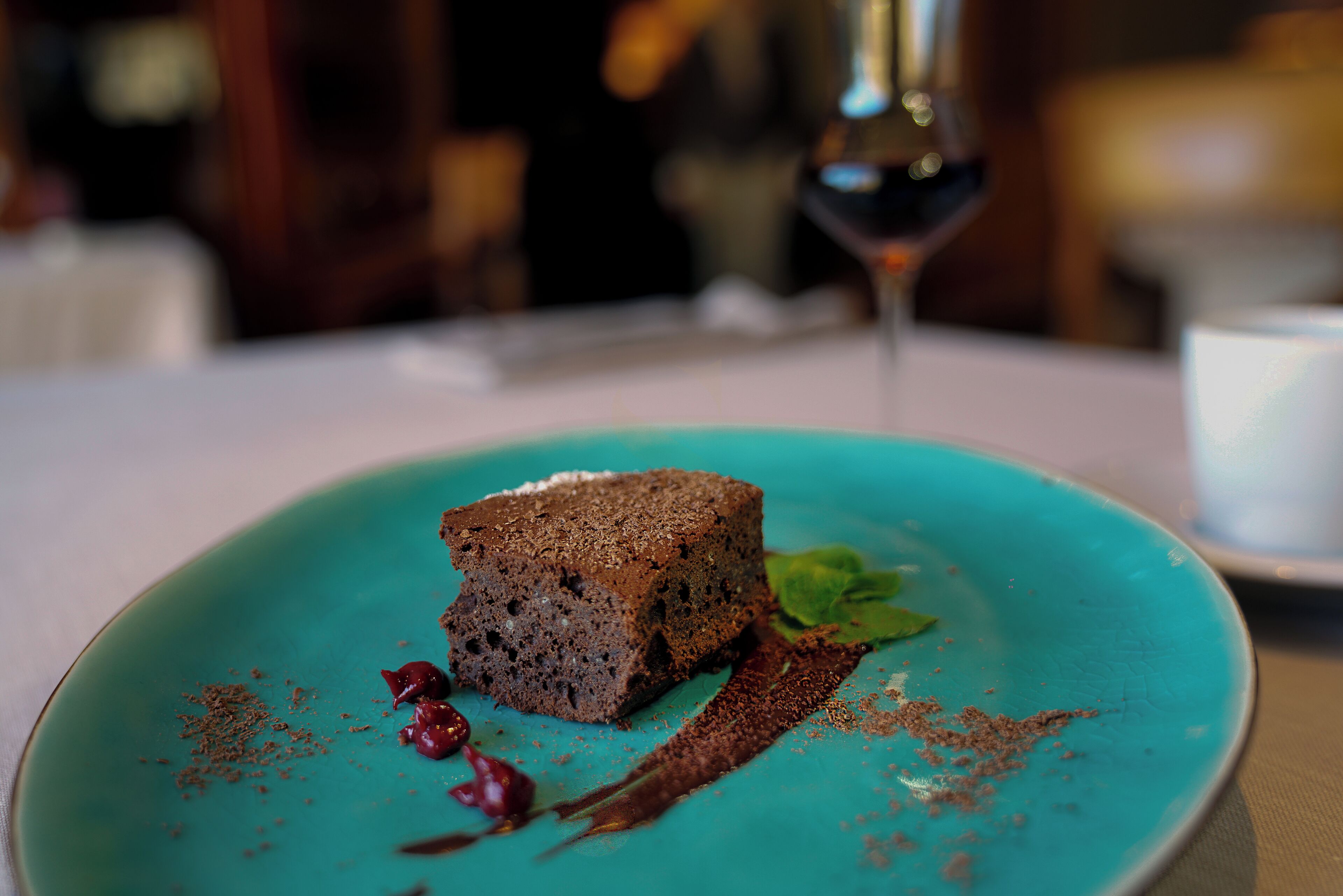 A dessert on a turquoise plate with chocolate shavings and berries.
