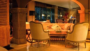 A cozy lounge area with a sofa and chairs, a coffee table, and a view of the city at night. - Hotel Swiss Moraira (Teulada)