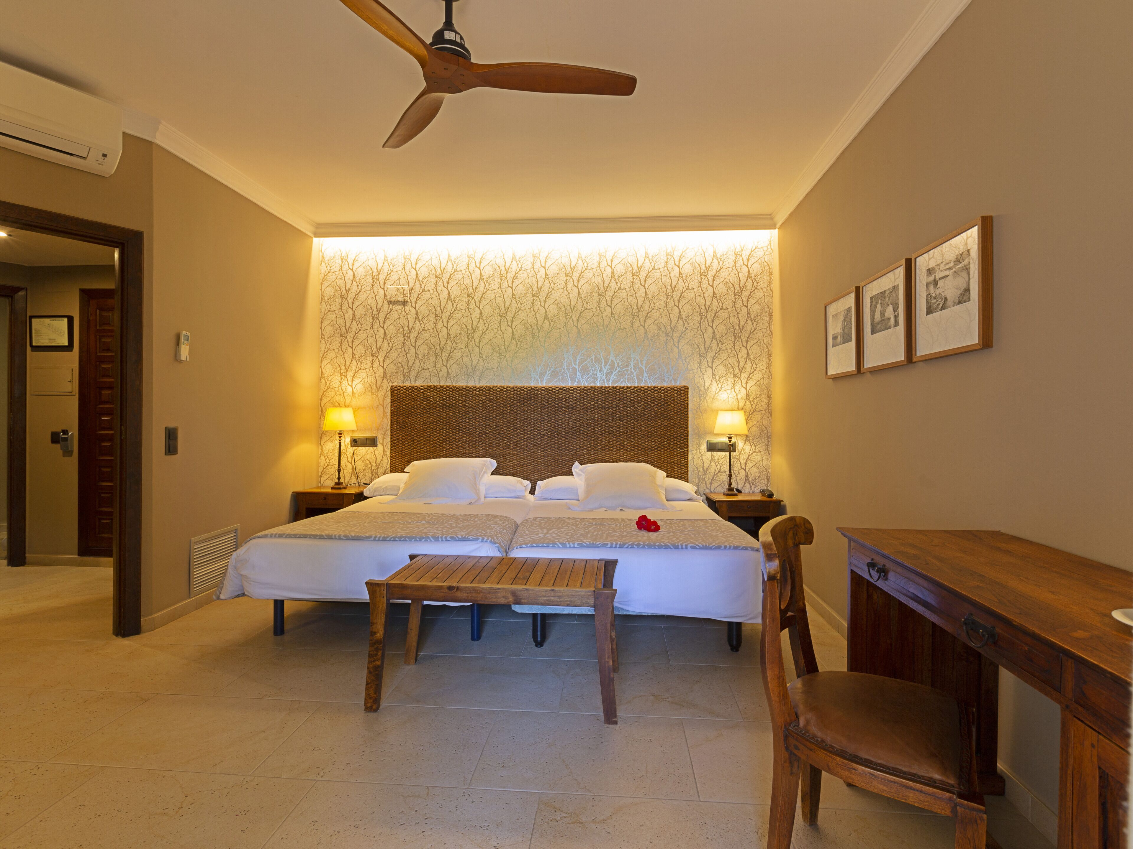Una habitación de hotel con una cama, lámparas de noche, un escritorio y una silla.